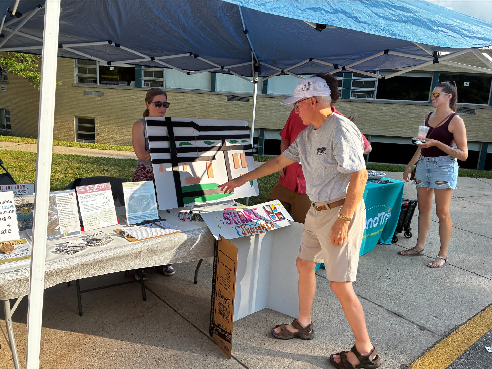 A neighbor pointing at a model of the Stoughton Road corridor on the booth table